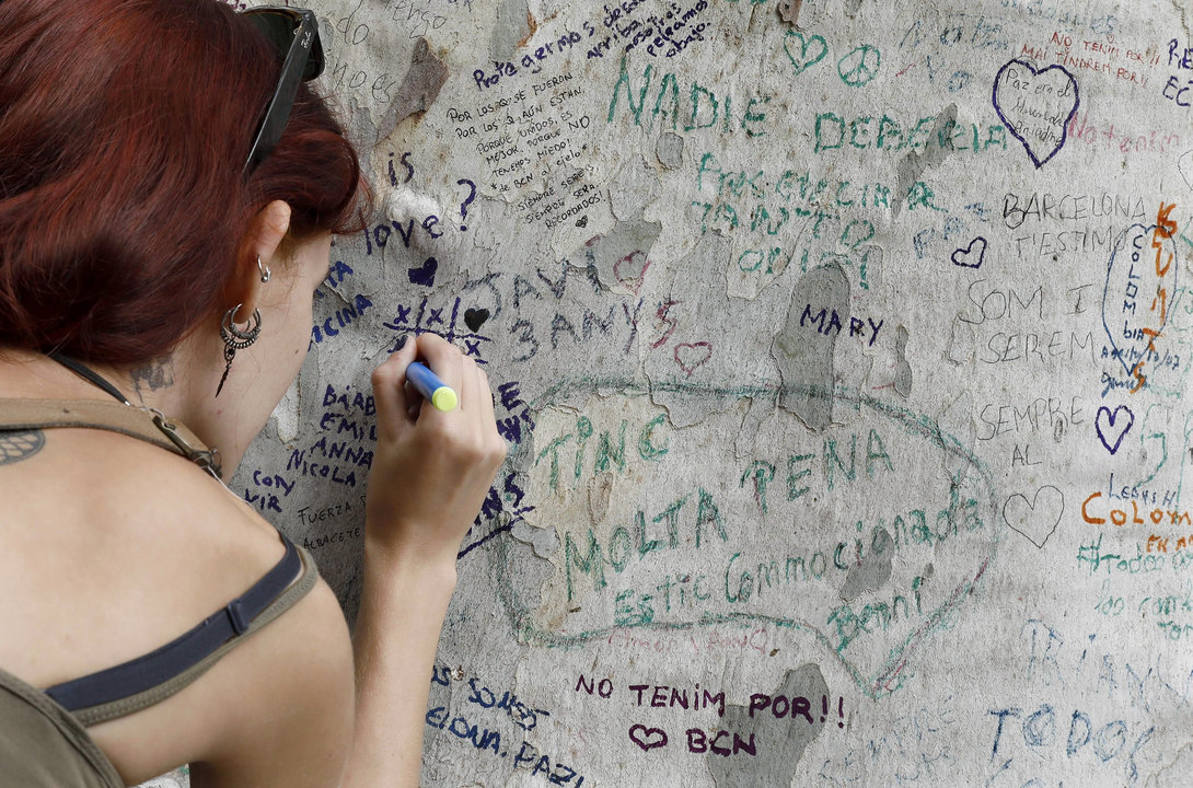 Una joven escribe un mensaje de solidaridad en el tronco de un árbol de la Rambla.