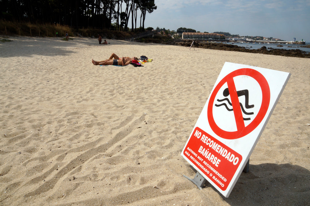 Un cartel desaconseja el baño en la playa de Serral, junto a Mirambell, desde ayer.