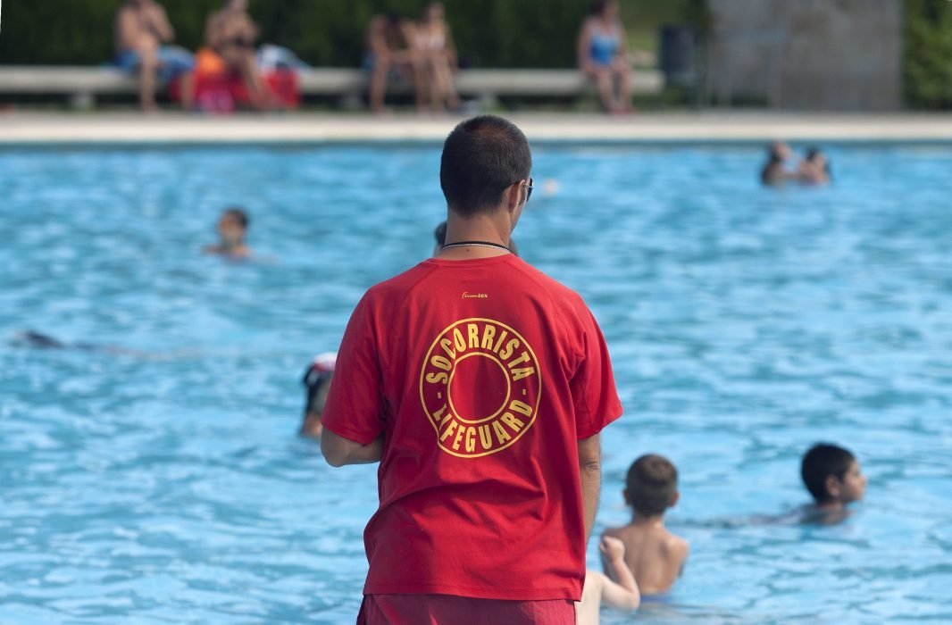 Un socorristas controla a los bañistas de una piscina municipal.