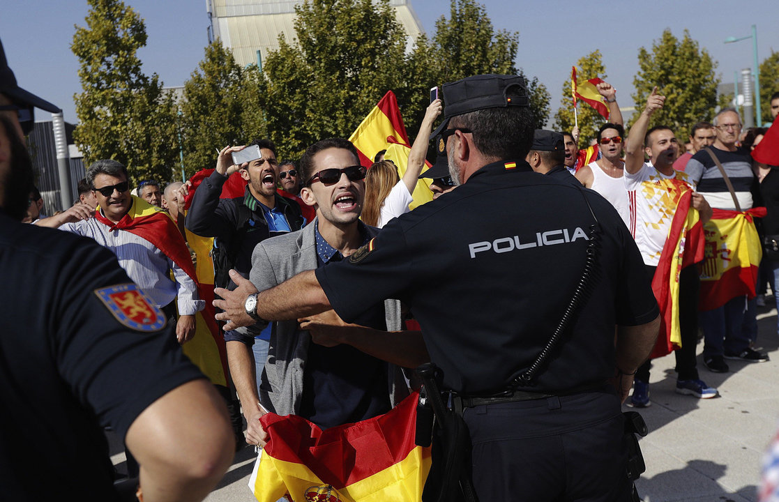 Un manifestante se encara con un agente de policía, en el exterior del pabellón de Zaragoza.