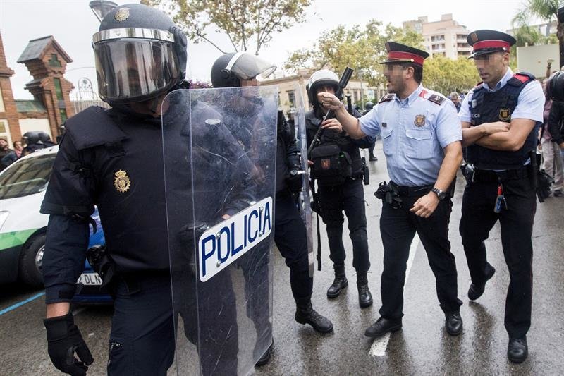 Agentes antidisturbios de la Policía Nacional y de los Mossos d' Esquadra discuten frente al Instituto Can Vilumara de L'Hospitalet de Llobregat.
