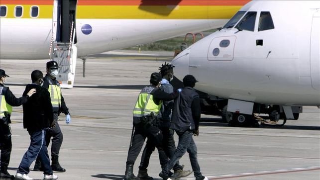 Agentes de la Policía Nacional llevan hacia un avión a inmigrantes que van a ser deportados.