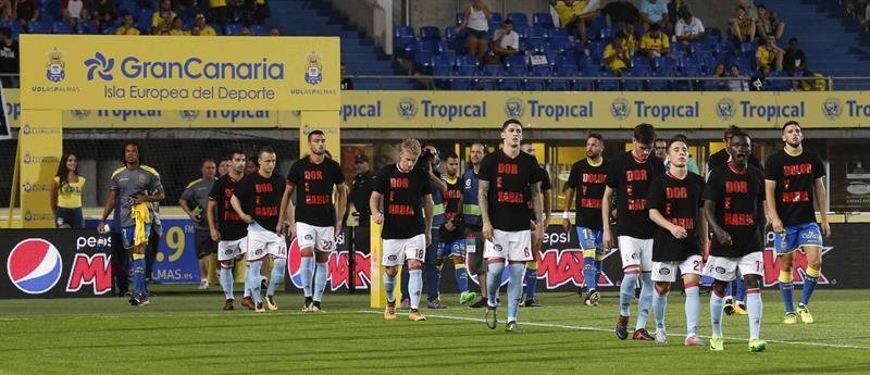 Los jugadores de Las Palmas, y del Celta de Vigo, saltan al campo con una camiseta negra con el lema &#34;Dolor y Rabia&#34; por los incendios de Galicia