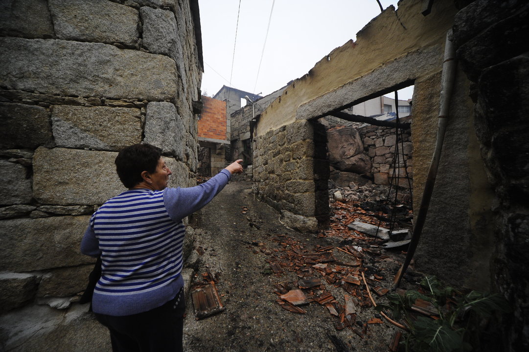 Una mujer indica la zona por la que entró el fuego en una vivienda de Muimenta (Carballeda de Avia).