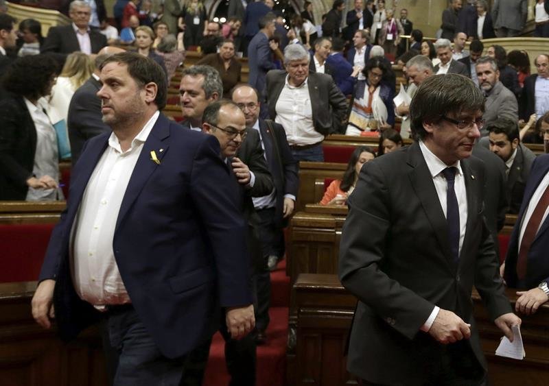 El presidente de la Generalitat, Carles Puigdemont, y el vicepresidente, Oriol Junqueras (i), abandonan el hemiciclo