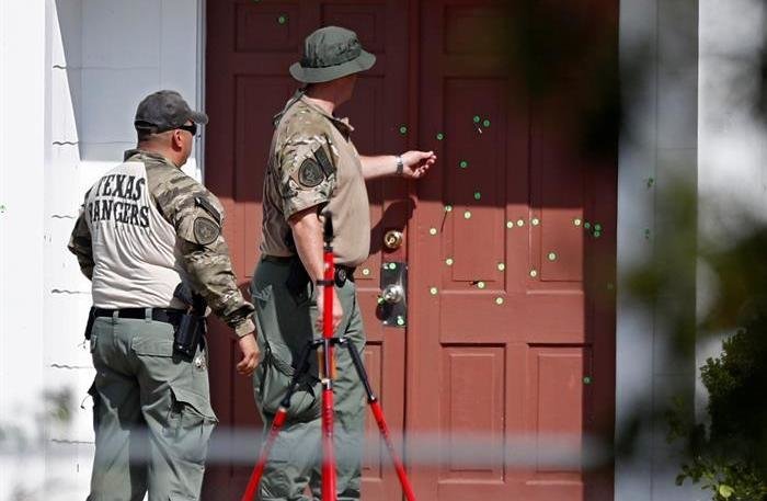Dos policías de Texas observan la puerta tiroteada de la iglesia baptista de Sutherland Springs.