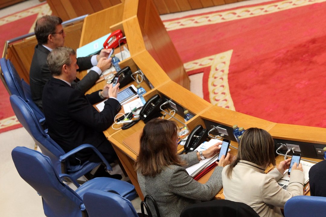 Feijóo, Rueda, Mato y Vázquez consultan sus móviles durante el pleno del Parlamento.