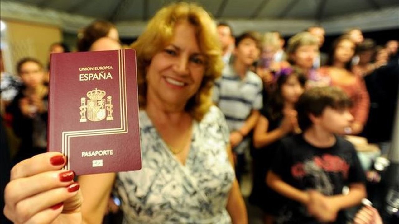 Una mujer brasileña muestra su pasaporte español después de jurar la Constitución.