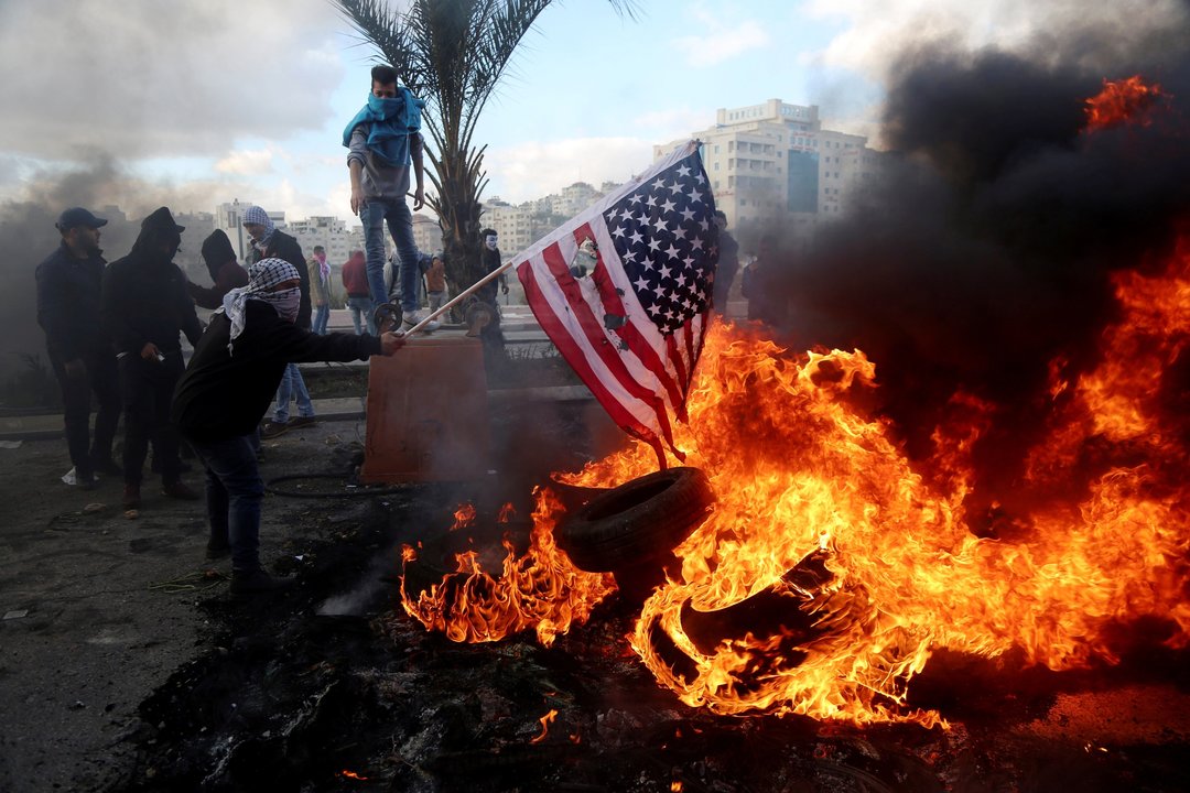 Un palestino quema una bandera estadounidense durante un enfrentamiento con tropas israelíes.