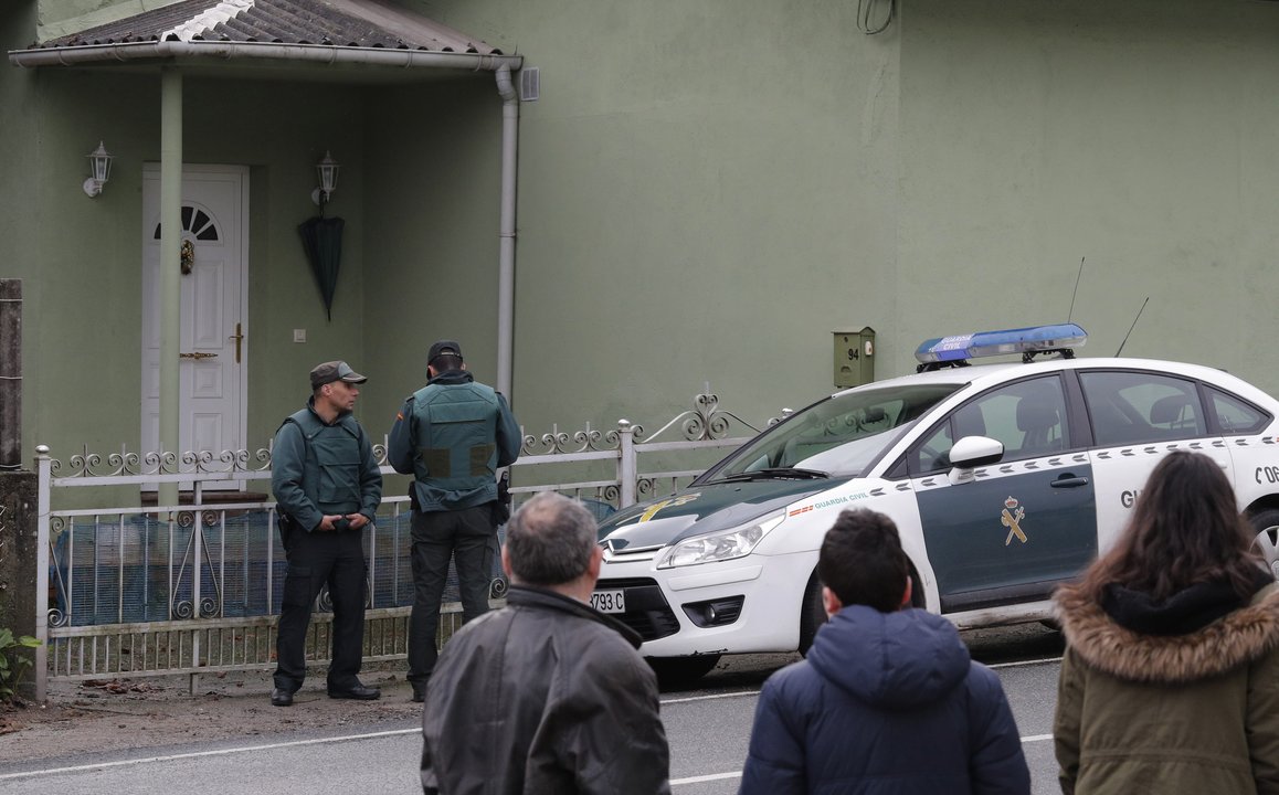 Tres vecinos de Taragoña observan el despliegue policial ante la casa de los detenidos.