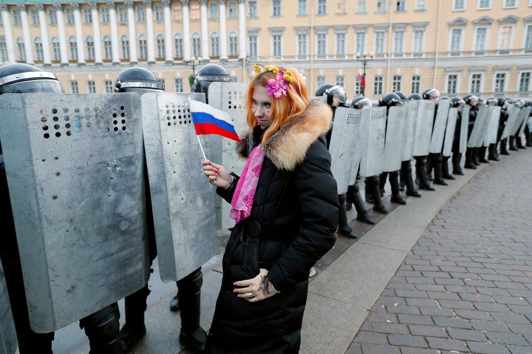 Una joven manifestante con una bandera de Rusia, delante de una fila de policías en San Petersburgo.