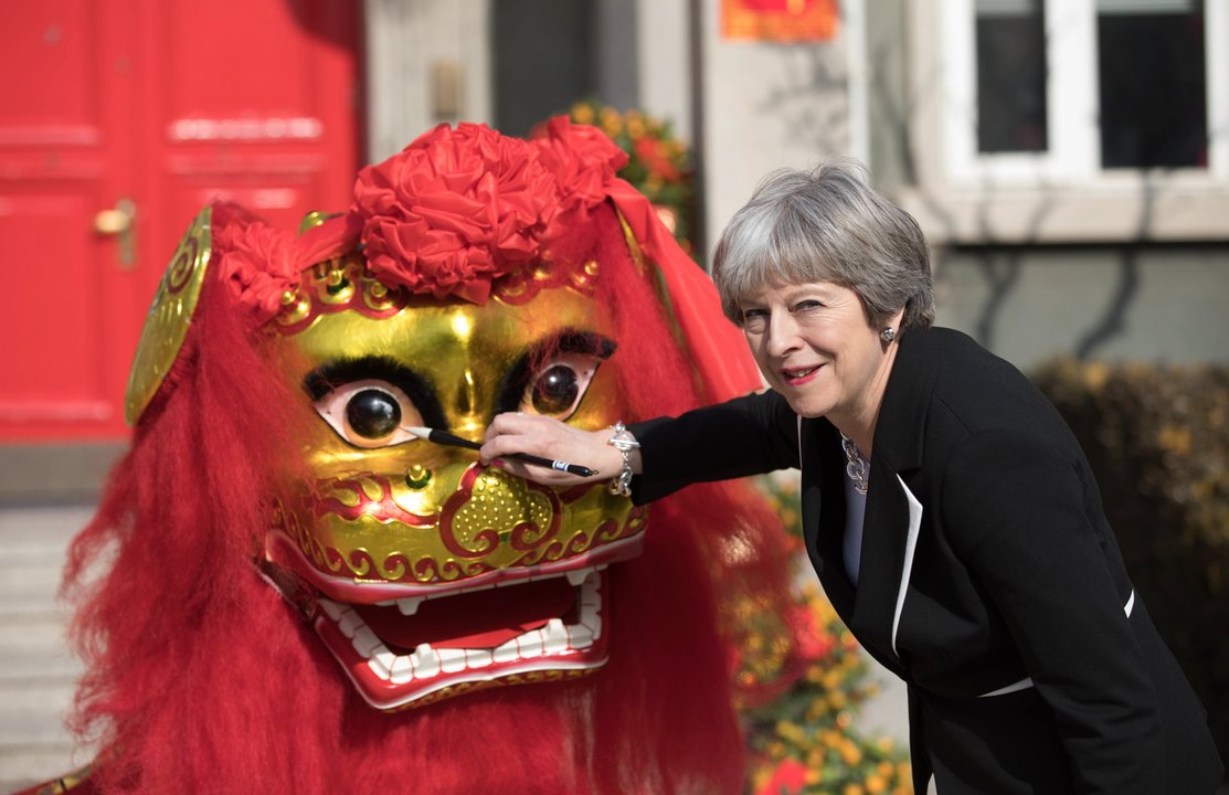La primera ministra británica, Theresa May, posa junto a un dragón chino durante su visita a Pekín.