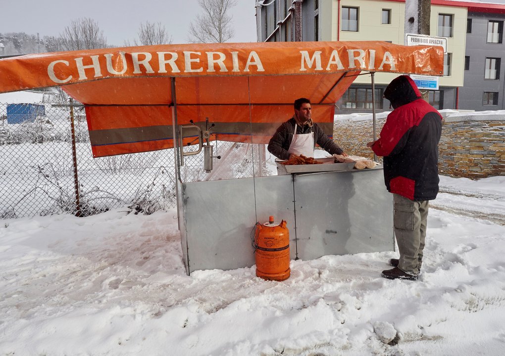 Un hombre vende churros en Pedrafita do Cebreiro, cubierta por una nevada.