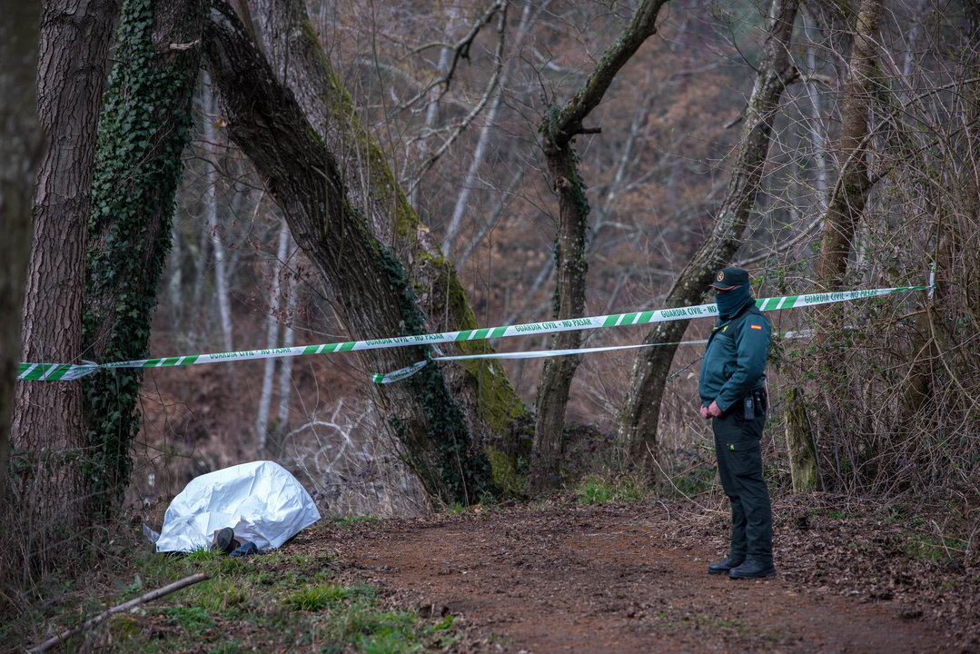 Un guardia civil custodia el cadáver tapado por una manta en el lugar en que fue hallado.