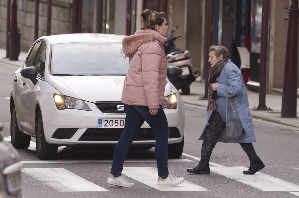 Una persona joven y otra mayor se cruzan esta semana en las calles de Vigo.