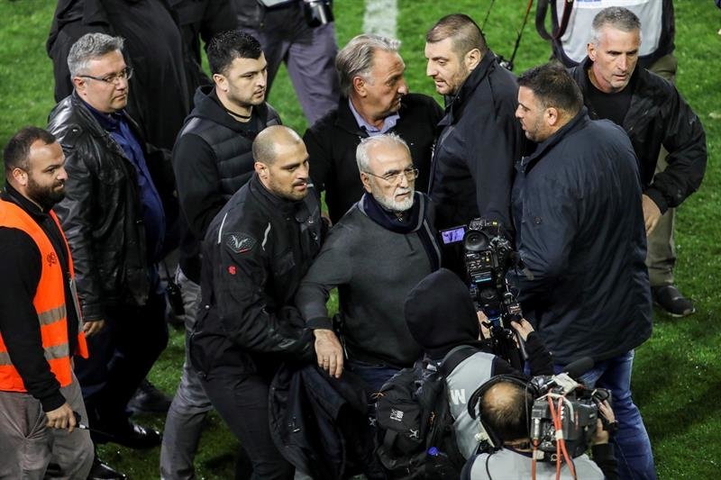 El presidente y propietario del PAOK griego, Ivan Savvidis (centro), abandona el terreno de juego escoltado por sus guardaespaldas