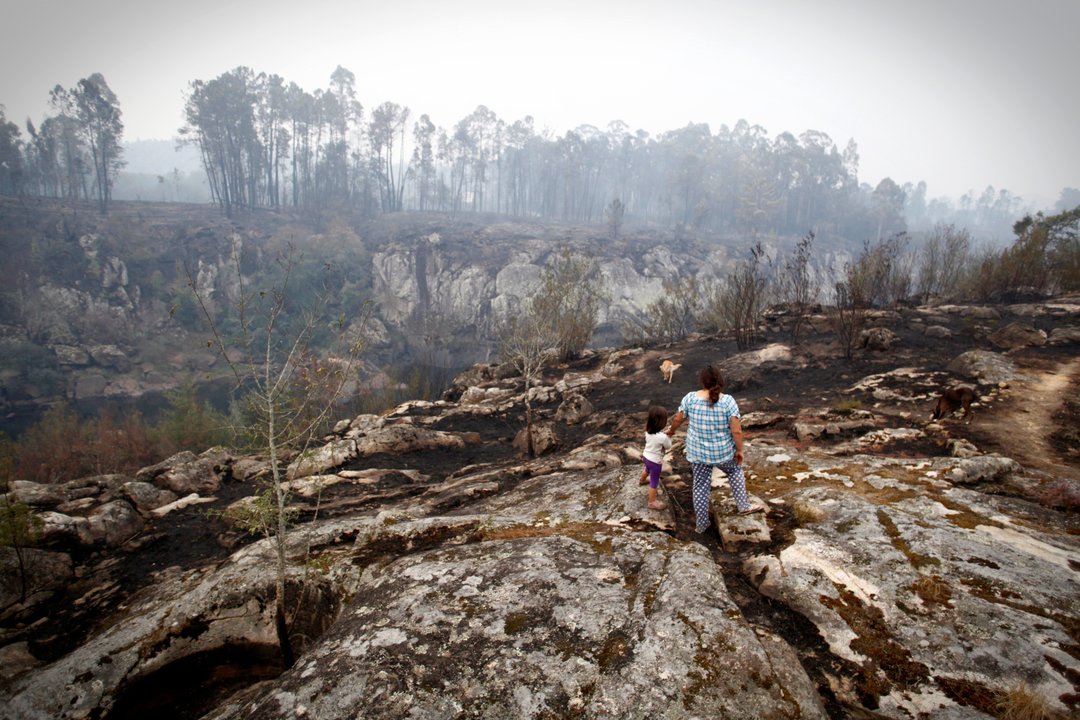 Una mujer y su hija observan los efectos del fuego en una zona de monte de As Neves.