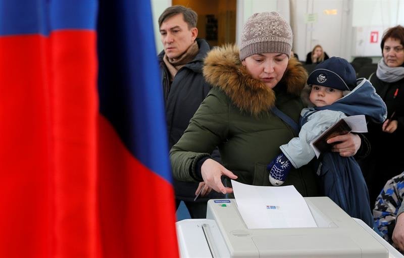 Un mujer acompañada de su hijo vota en Rusia
