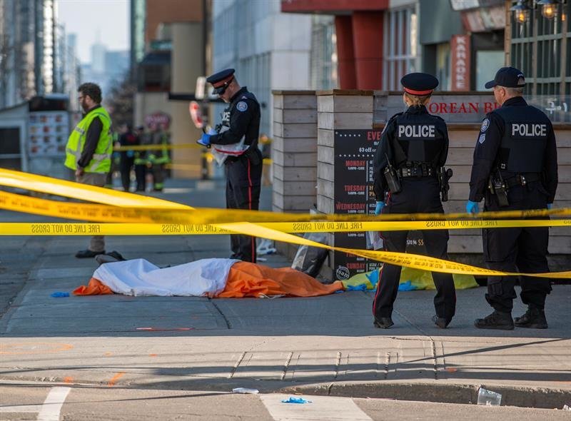 Oficiales de la policía de Toronto vigilan frente a un cuerpo cubierto