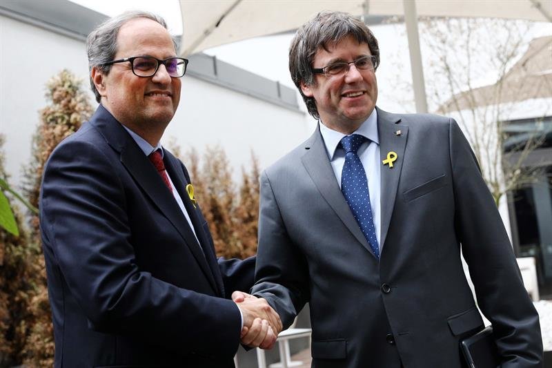 El recién elegido presidente de la Generalitat de Cataluña, Quim Torra (izq), estrecha la mano a su predecesor, el expresidente regional catalán Carles Puigdemont