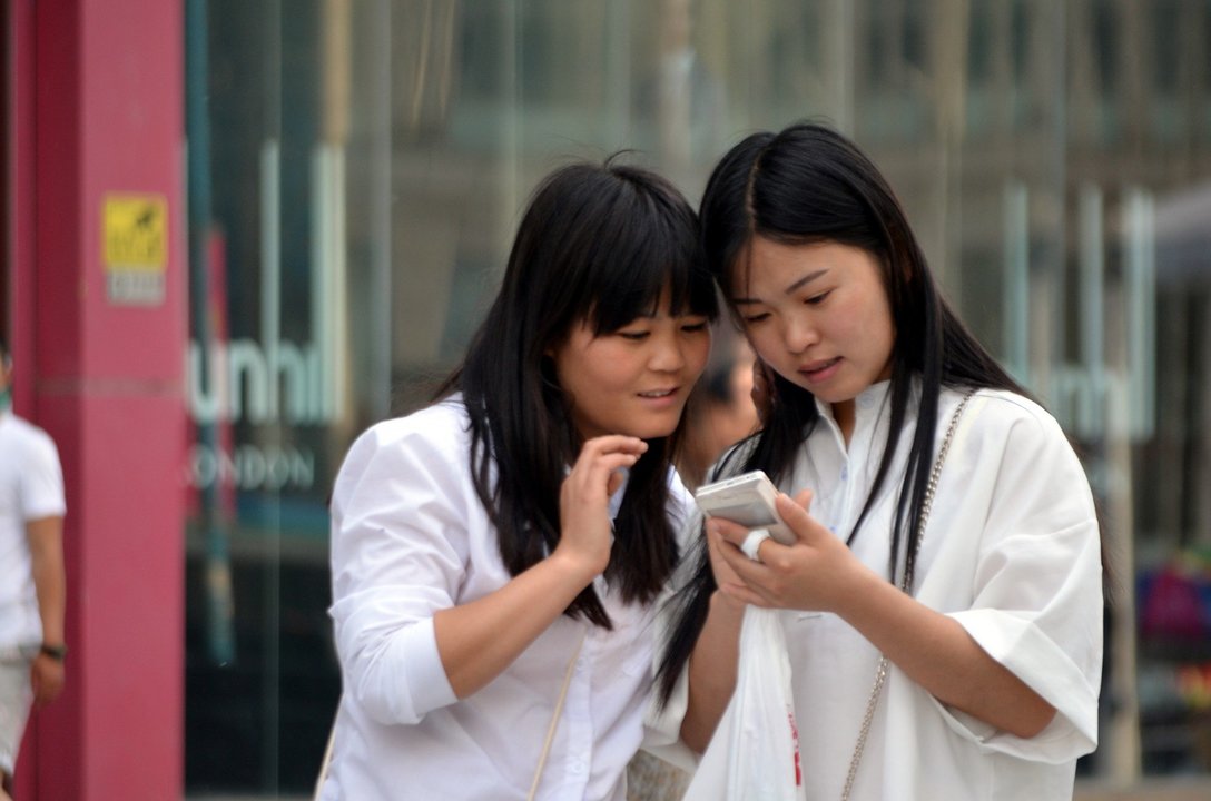 Dos jóvenes utilizan su smartphone en la calle.