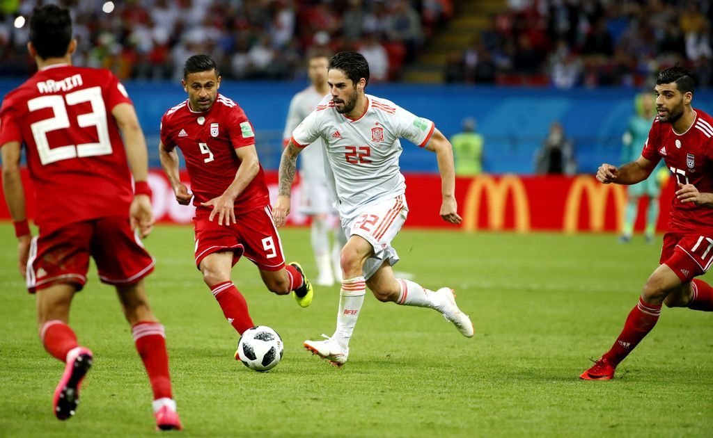 Isco conduce un balón perseguido por un jugador iraní.