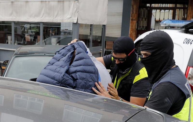 Agentes de Policía Nacional trasladan a un detenido durante el registro de un local de hostelería en Boiro (A Coruña)