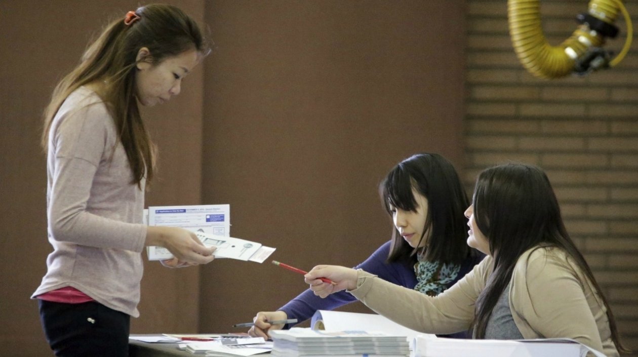Una mujer chinoestadounidense, en el momento previo a depositar el voto en la urna.