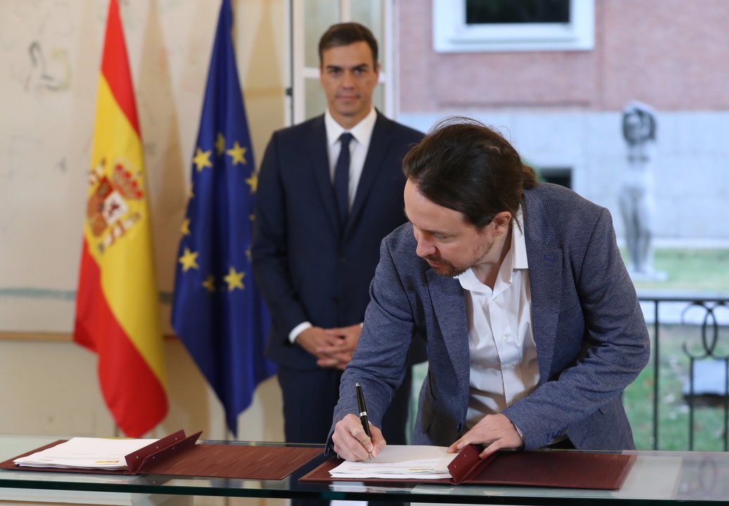 Iglesias suscribe el acuerdo en presencia de Sánchez.