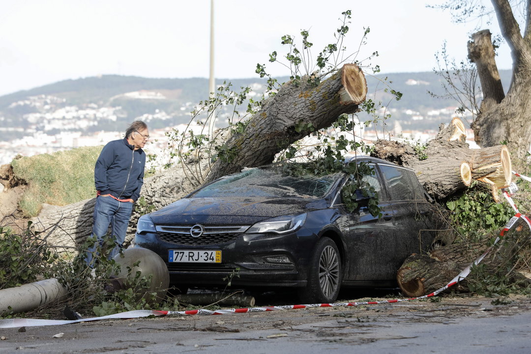 Un hombre observa el estado de un vehículo después de que le cayera un árbol en Figueira da Foz.