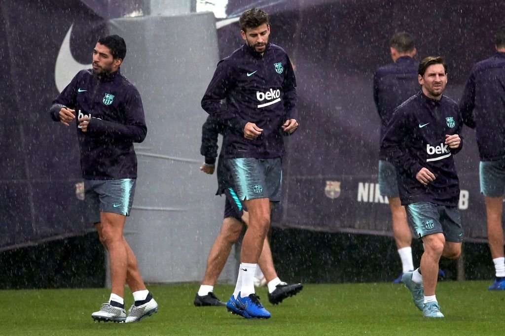 Luis Suárez, Piqué y Messi se ejercitan, ayer, bajo la lluvia.