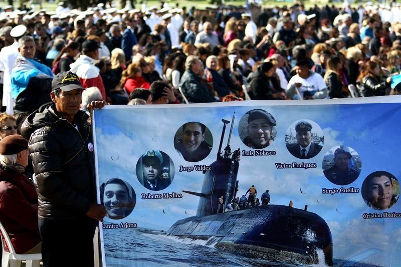Un hombre sostiene una pancarta con imágenes de algunos tripulantes del submarino argentino ARA San Juan
