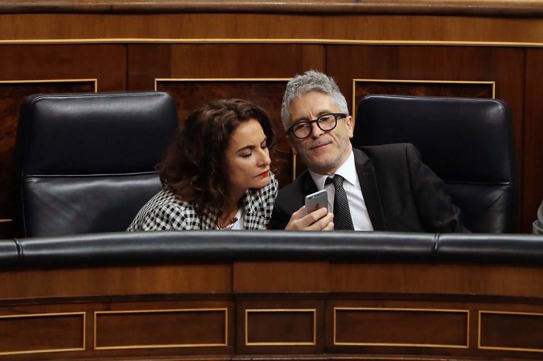 Montero y Grande-Marlaska observan un móvil en la sesión de control al Gobierno en el Congreso.