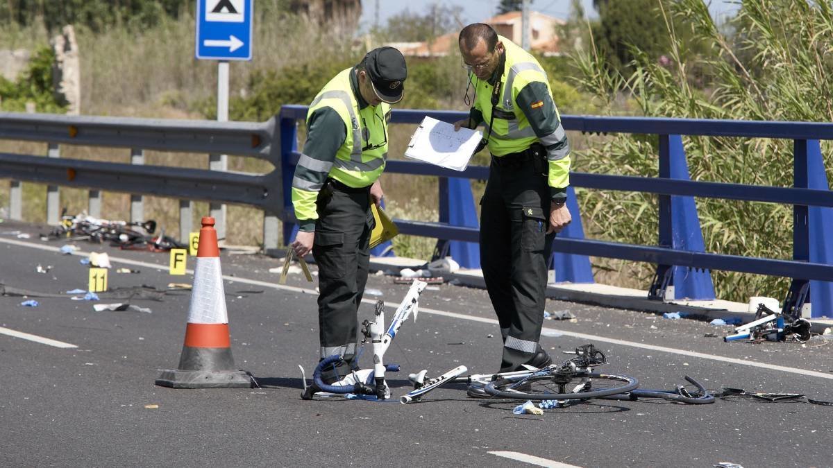Dos guardias civiles observan restos de bicicletas después de un atropello de ciclistas en Valencia.
