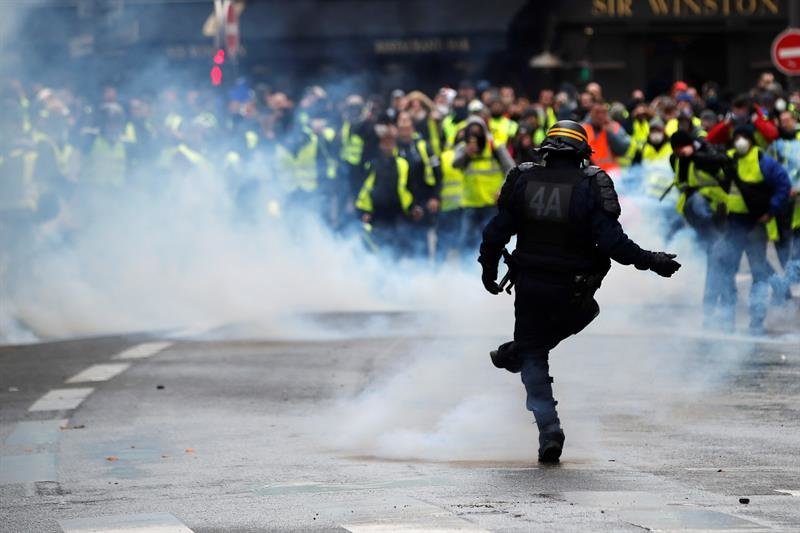 Un oficial de la policía antidisturbios francés patea una paleta de gas lacrimógeno que les fue arrojada durante una manifestación de Yellow Vest en París, Francia