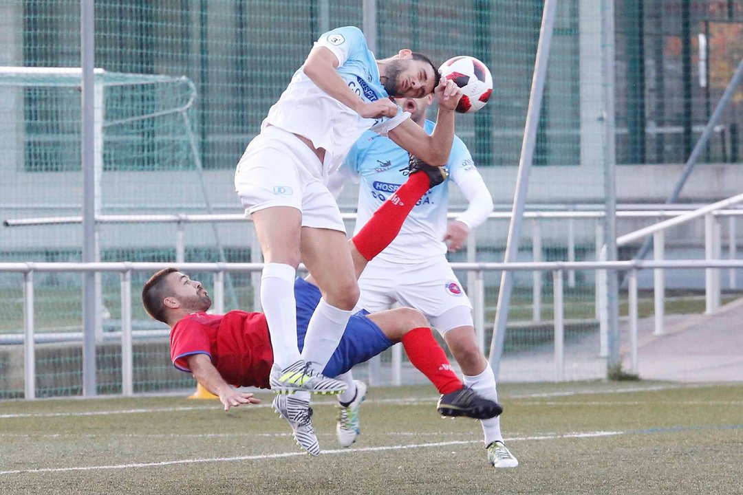Un futbolista da UD Ourense saca o balón ante o intento de remate de Comis.