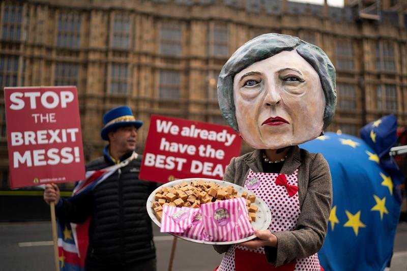Una activista contraria al &#34;brexit&#34; disfrazada de la primera ministra británica, Theresa May, posa con un plato con &#34;fudge&#34;, un caramelo blando parecido al dulce de leche, delante del Parlamento en Londres