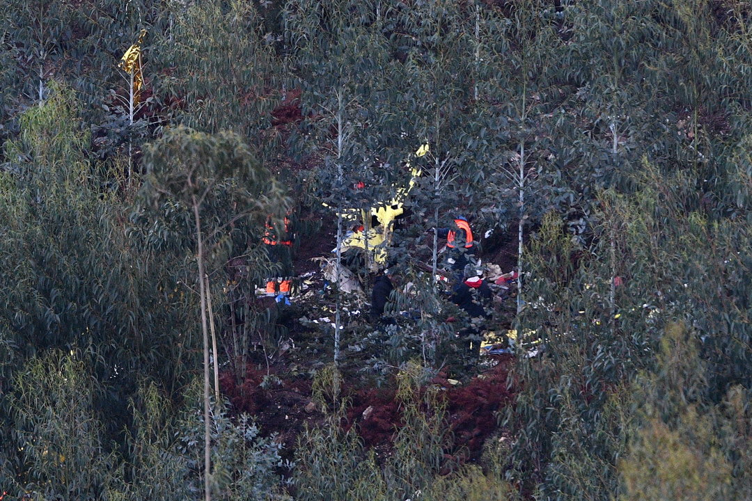 Miembros de los servicios de rescate, ante los restos del helicóptero en el lugar del accidente.