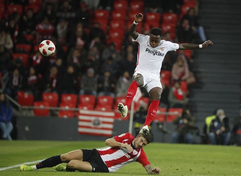 El defensa del Athletic Club de Bilbao, Unai Núñez (i), disputa un balón con el delantero neerlandés del Sevilla FC, Quincy Promes (d),