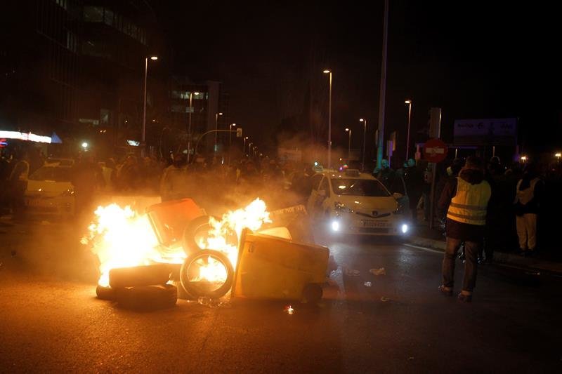 Los taxistas queman contenedores a la entrada de IFEMA, en la jornada de apertura de Fitur