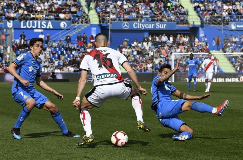 El defensa del Rayo Vallecano Jordi Amat (c) con el balón ante los jugadores del Getafe Jaime Mata y Damián Suárez