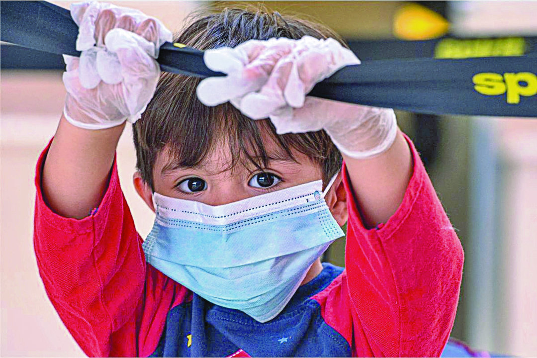 Un niño con guantes y mascarilla juega en una sala de recreo de un hospital.