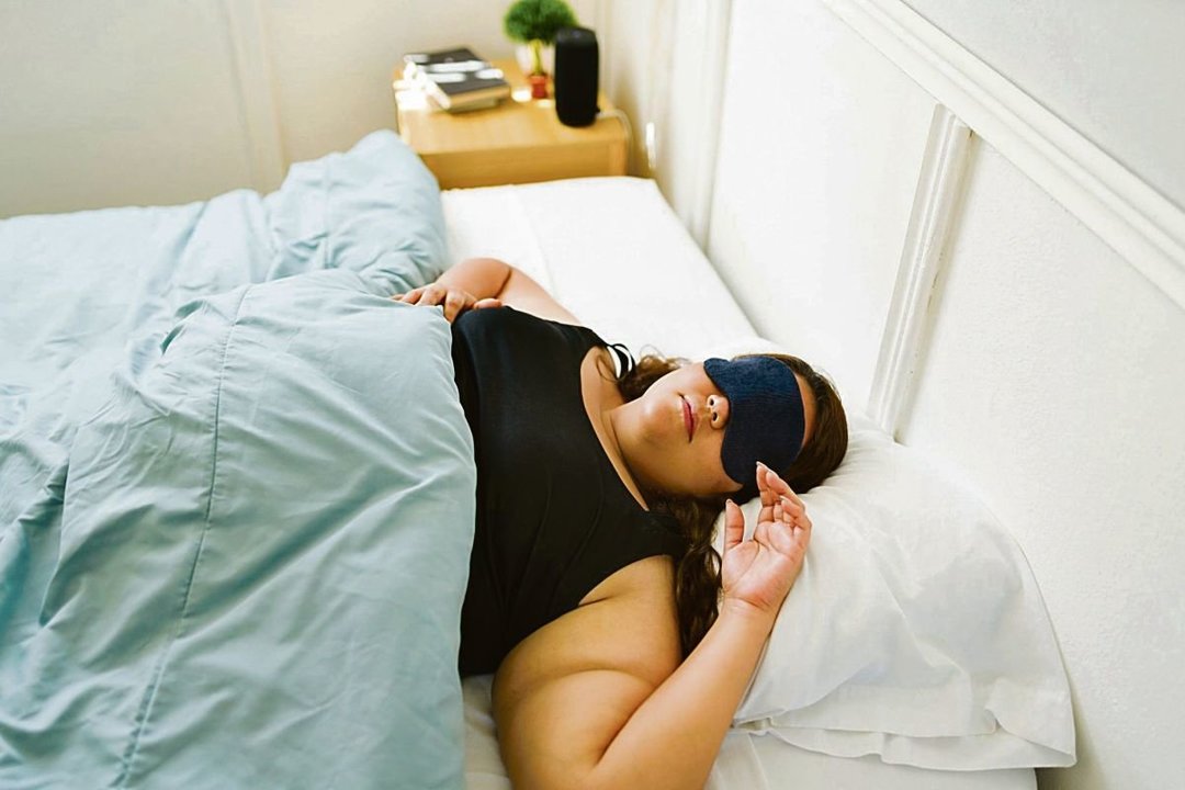 Una mujer utiliza un antifaz para evitar la luz y poder dormir.