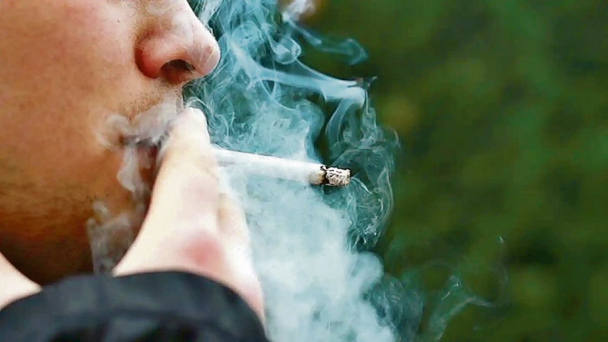 Un hombre joven fuma un cigarrillo.