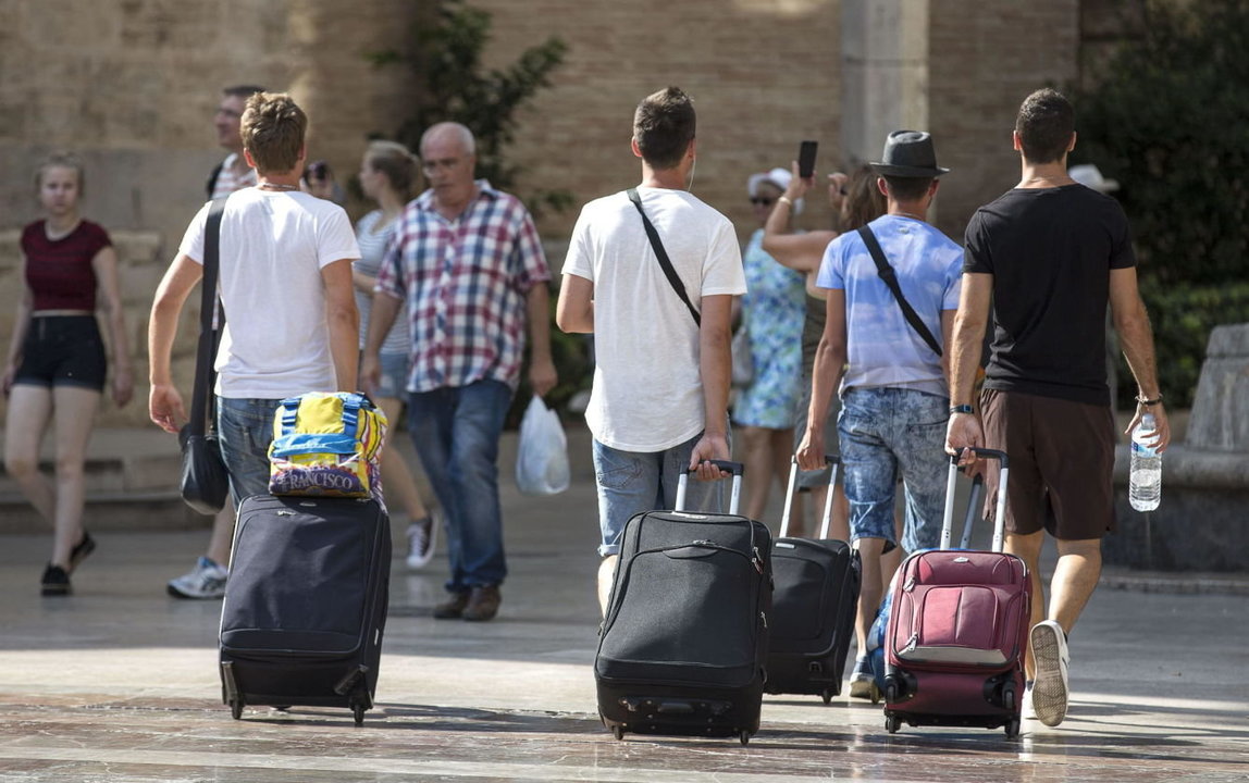 Un grupo de turistas carga su equipaje dirigiendose a su alojamiento.