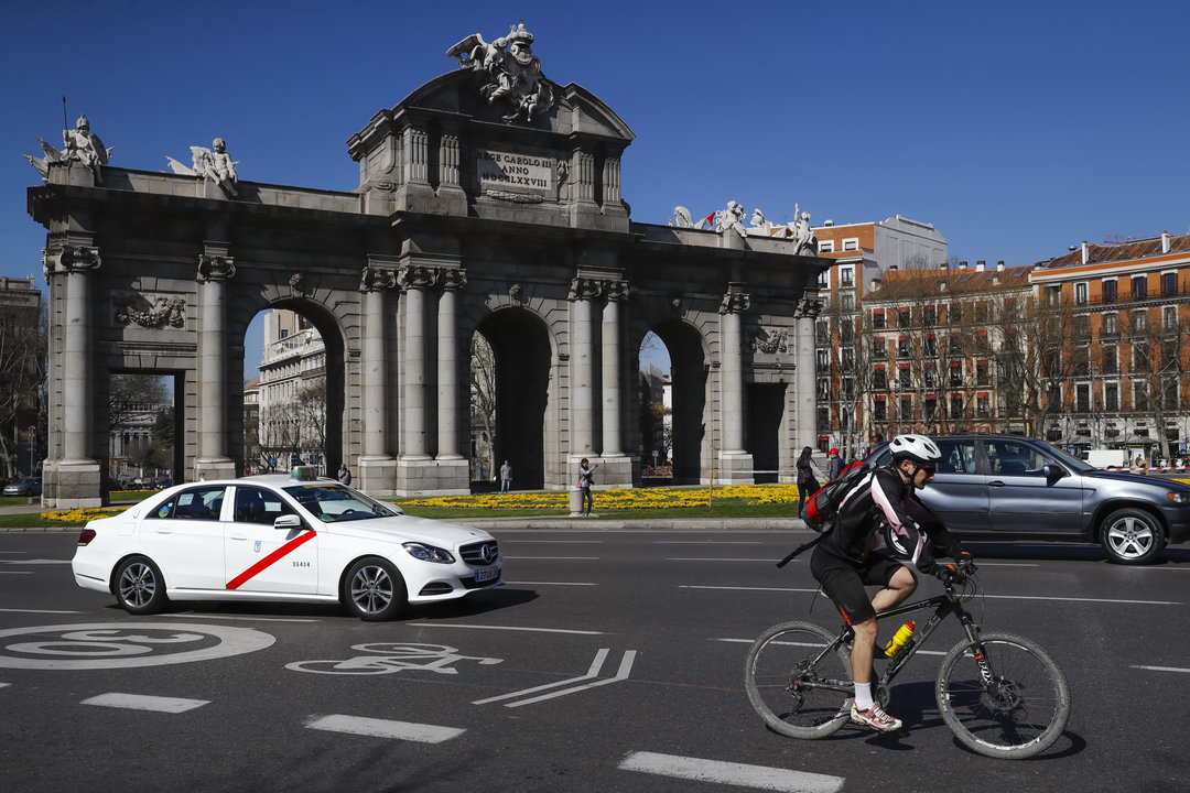 Un ciclista circula por un carril bici ante la Puerta de Alcalá de Madrid.