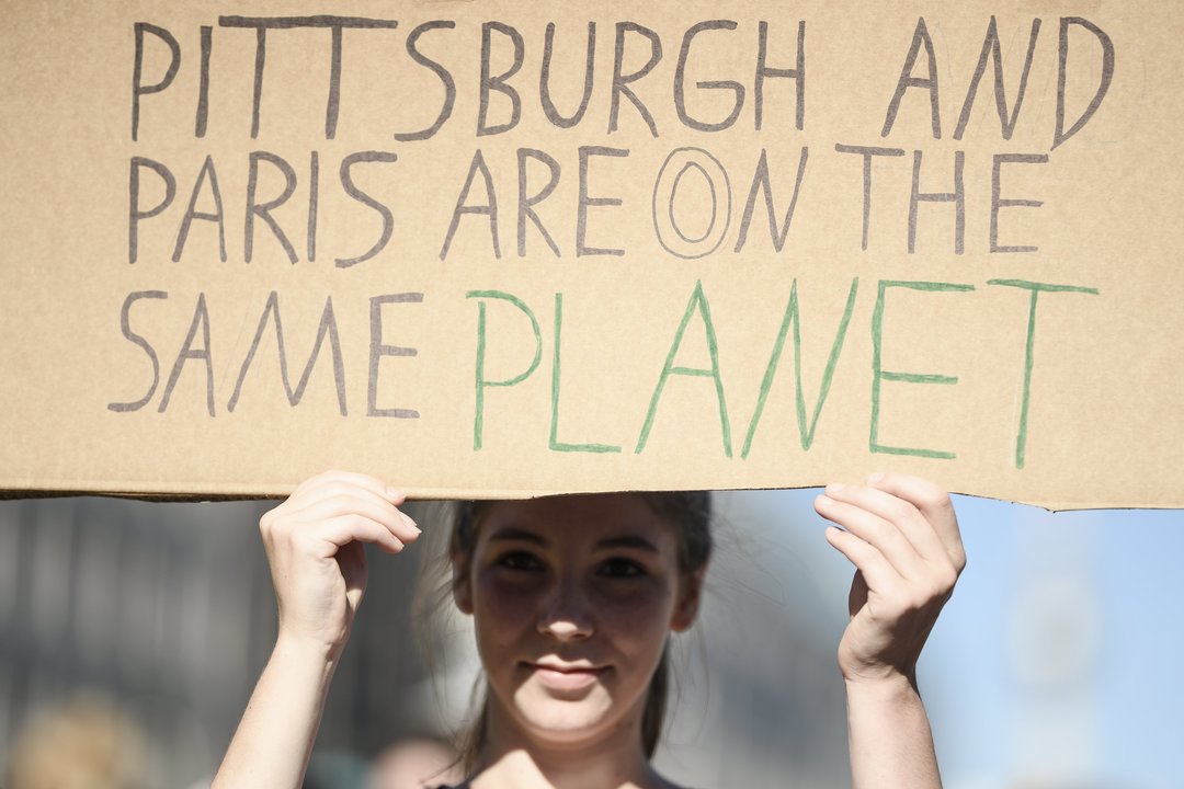 Una manifestante sostiene una pancarta en la que se lee &#39;Pittburgh y París están en el mismo planeta&#34;.