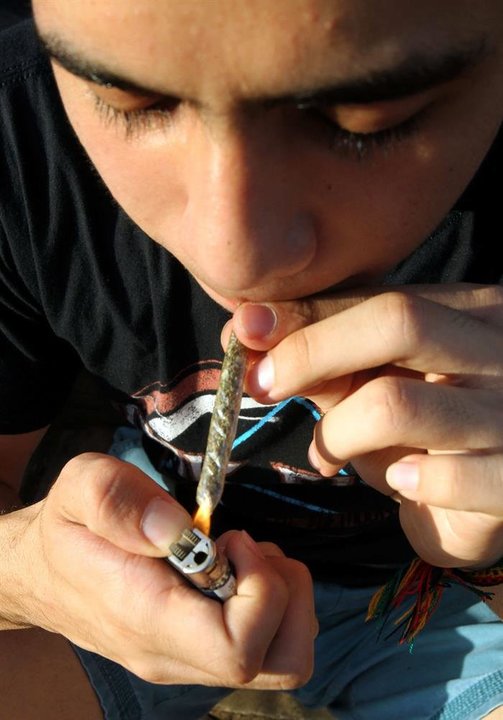 Un joven en el momento de encender un cigarro de cannabis.
