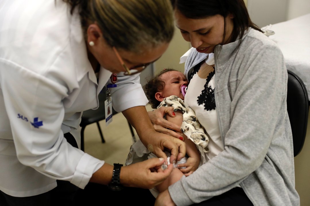 Una enfermera vacuna a un bebé contra el sarampión.