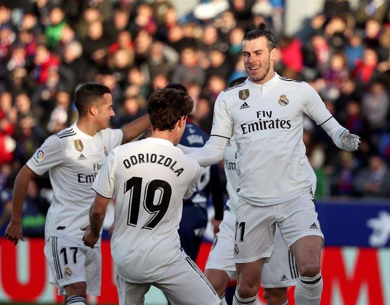 Gareth Bale (d) celebra con sus compañeros, Odriozola y Lucas Vázquez (i) su gol ante el Huesca